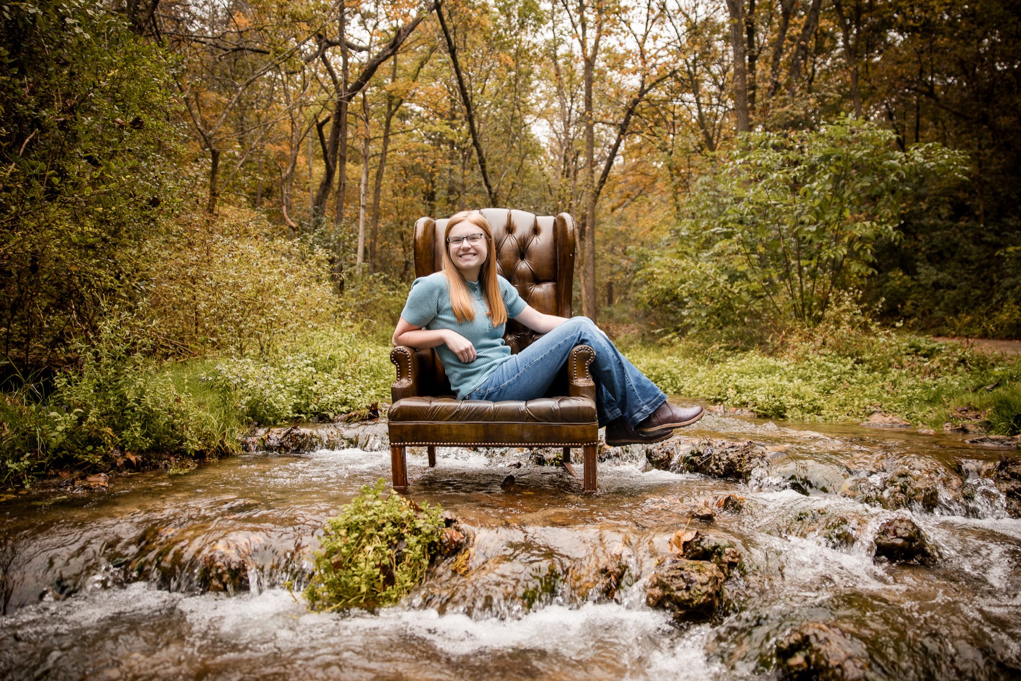 Hannah in a leather wingback chair set in the middle of a rocky creek