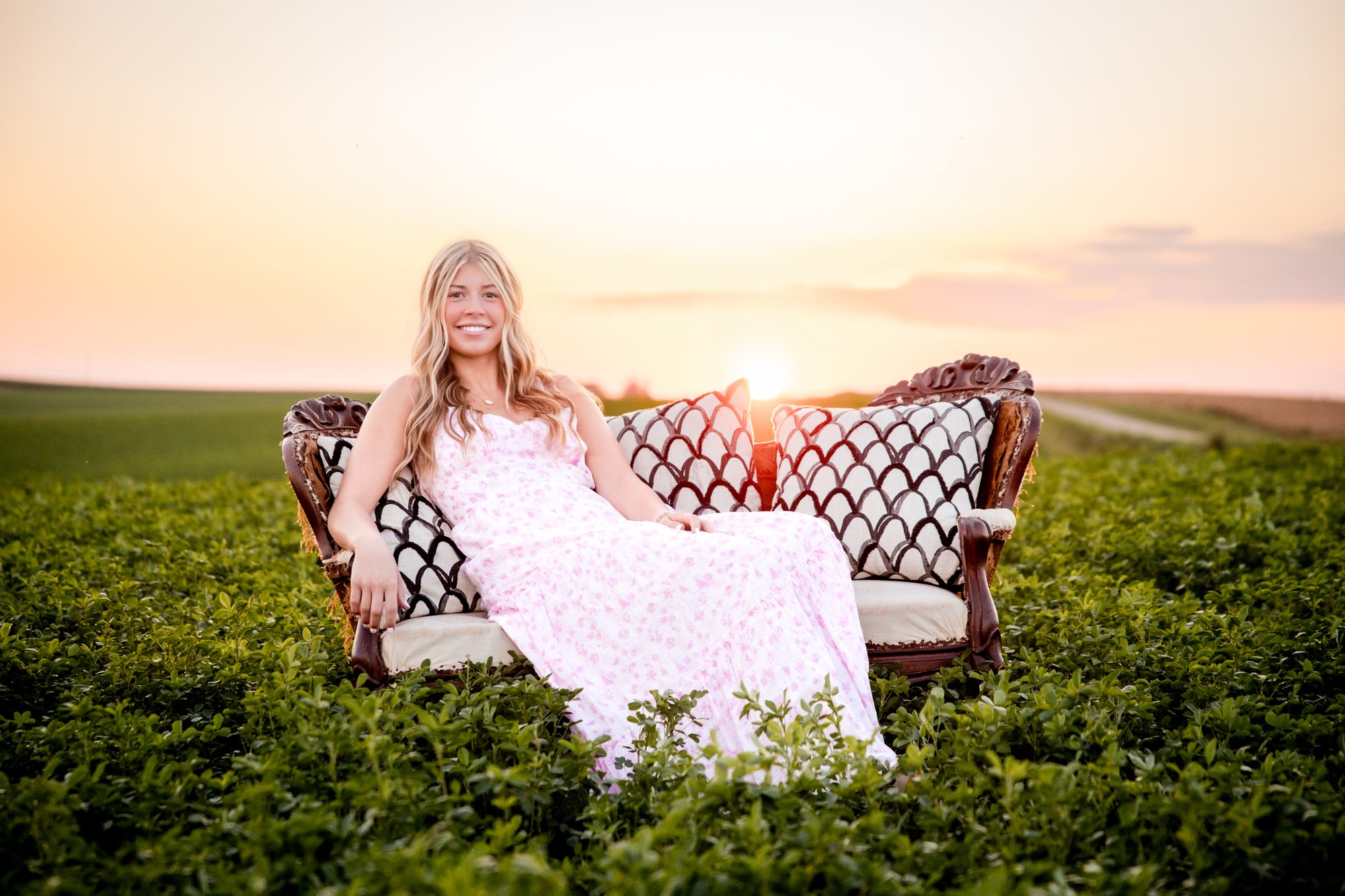 Katie on a vintage couch in a field at sunset