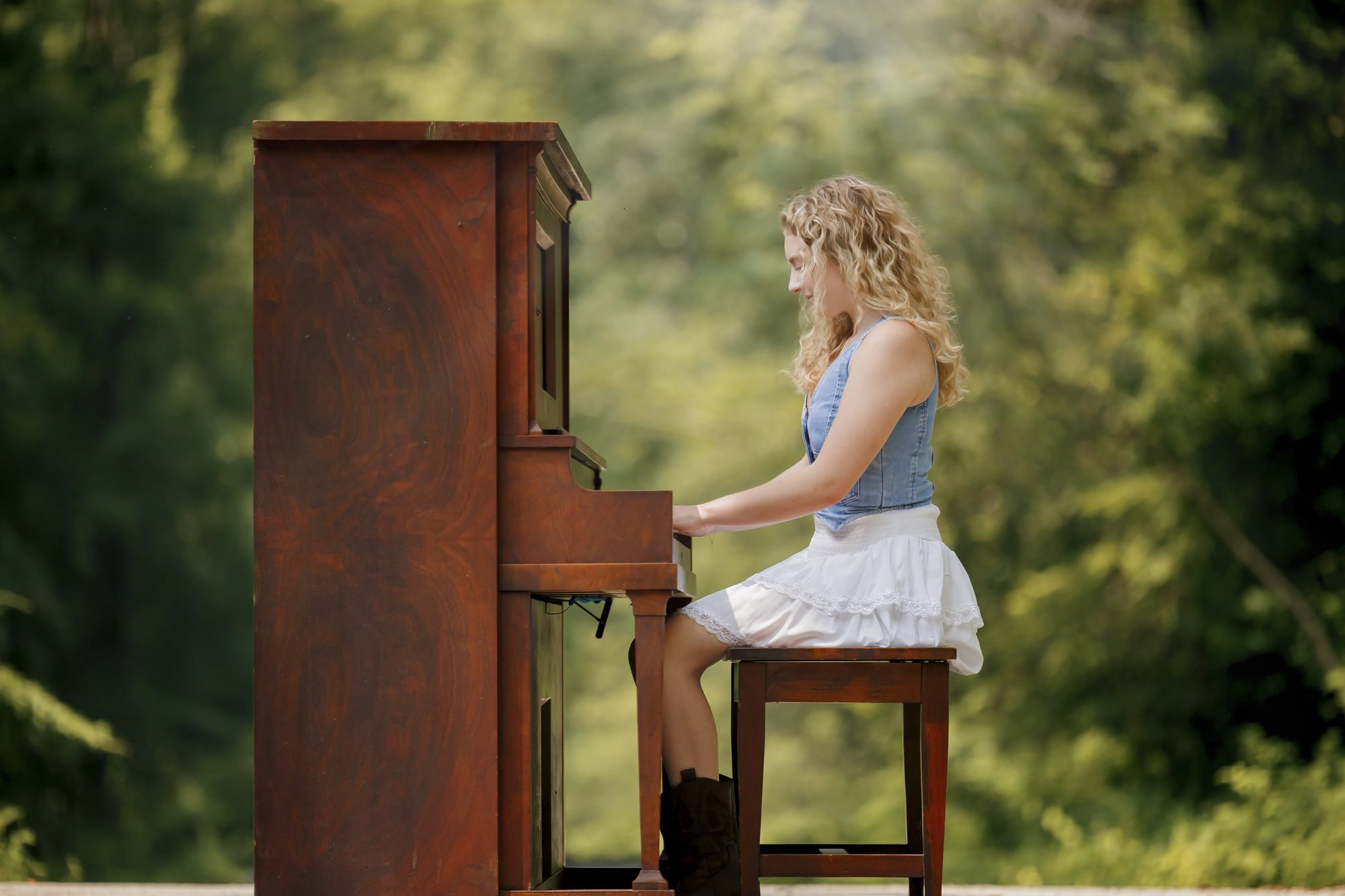 Teagan at an upright piano on a wooded path