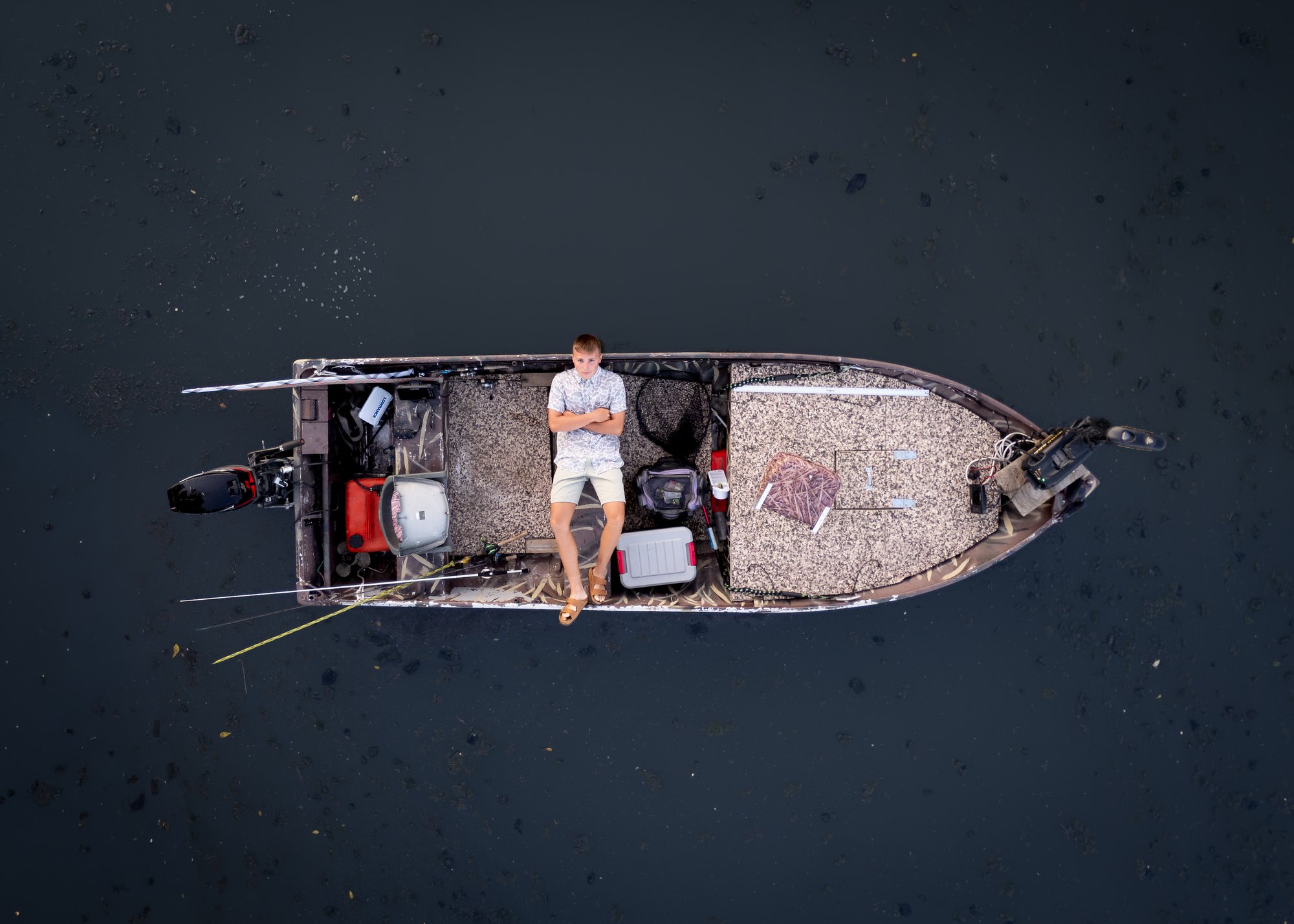 Overhead drone photo of Jax Tommasin in his fishing boat on dark water