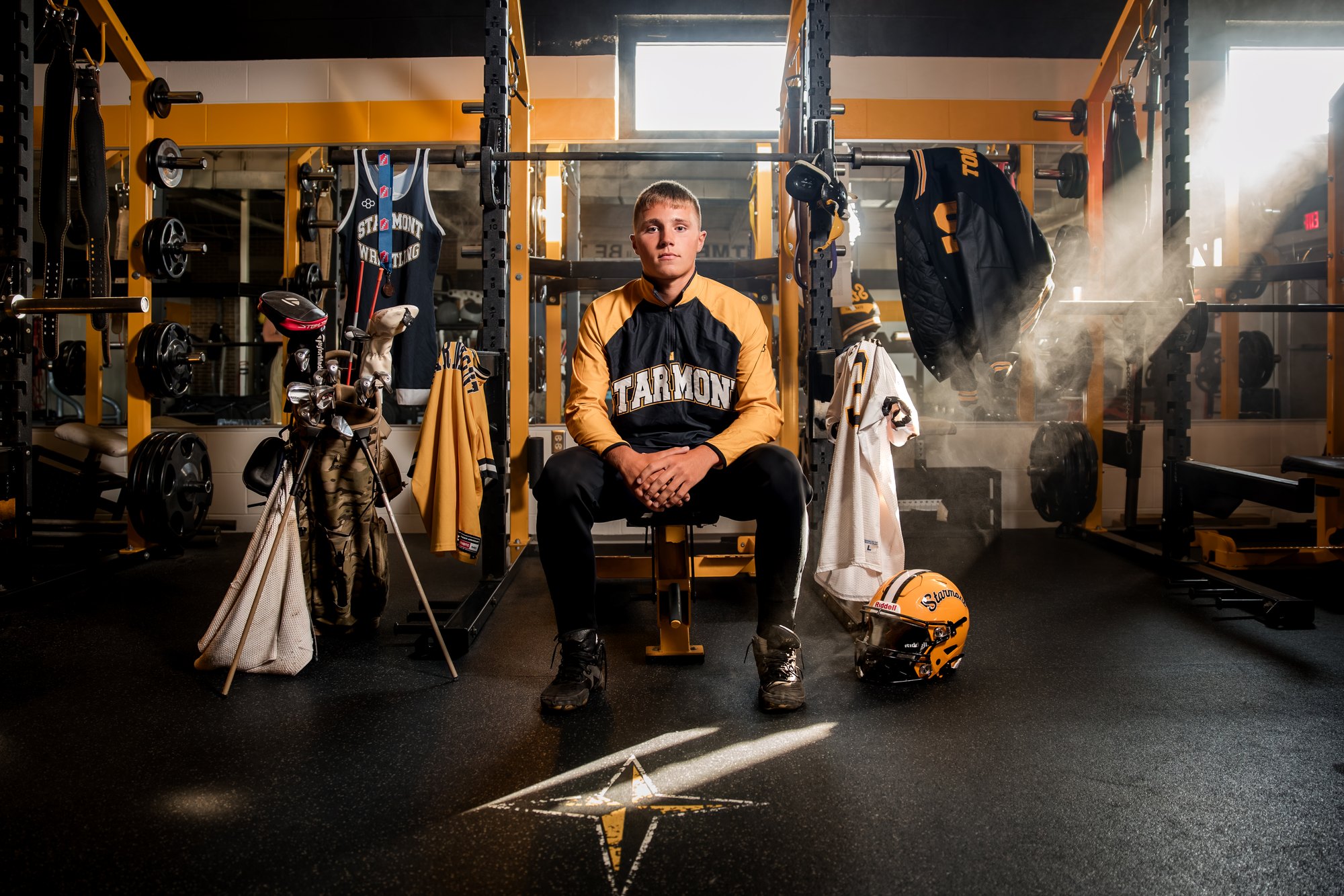 Jax Tommasin seated in the Starmont weight room, surrounded by his football, wrestling, and golf gear