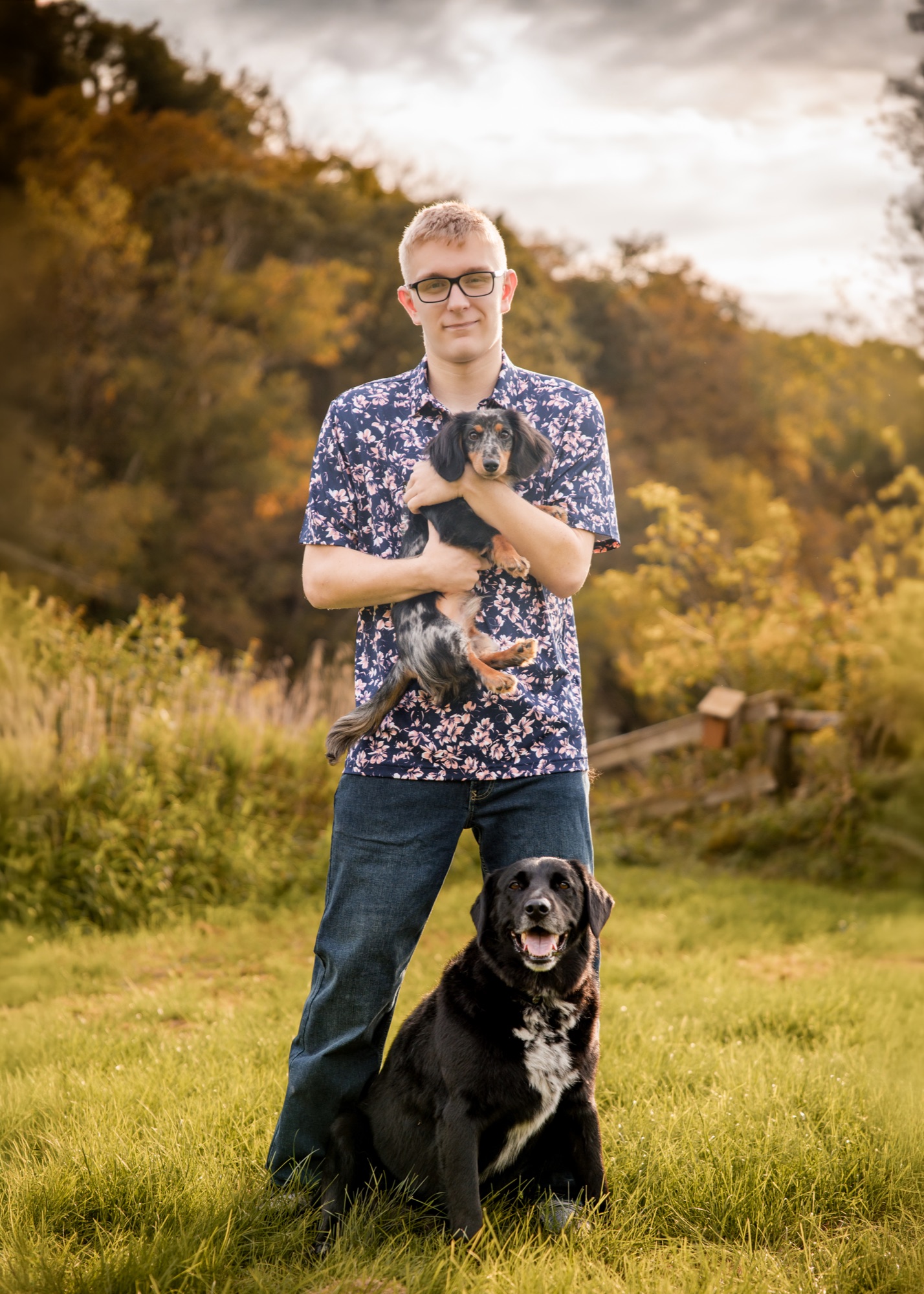 Tucker holding a puppy with his black lab sitting at his feet
