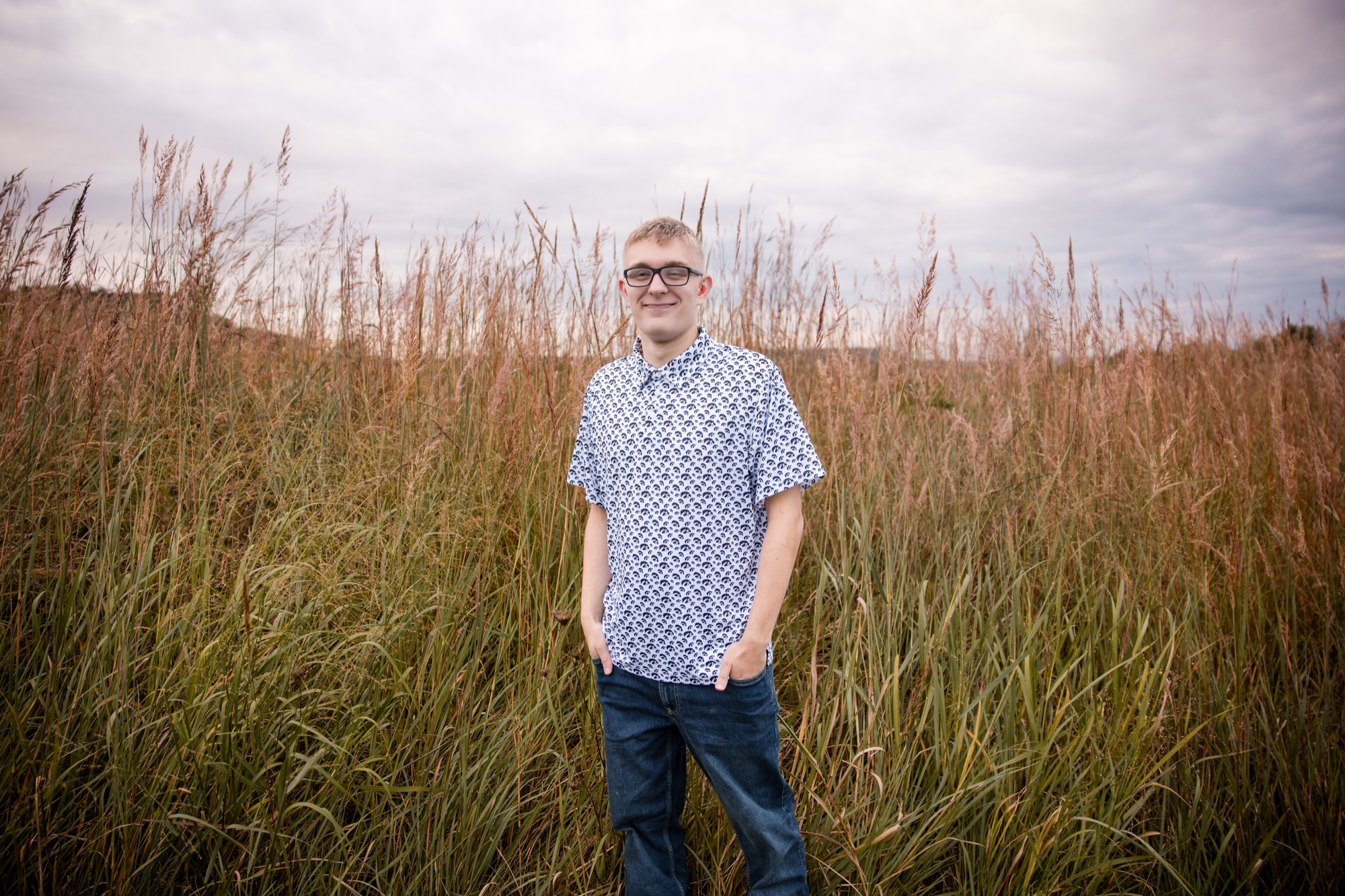 Tucker standing in tall prairie grass under a cloudy sky